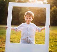 A boy is holding a frame in a park