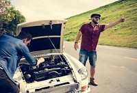 Man Hitch Hiking on The Street Side Near The Broke Down Car