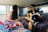 Man Playing Guitar with Lover in a Van Road Trip