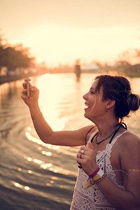 Caucasian woman taking photo sunset