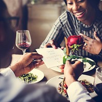 Man proposing with a red rose at the dinner table