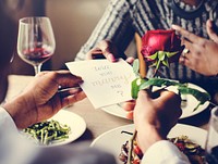 Man proposing with a red rose at the dinner table