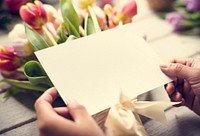 Hands Holding Design Space Empty Card with Tulips Flowers as Bac