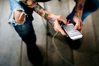 Close up of tattooed hands using mobile phone