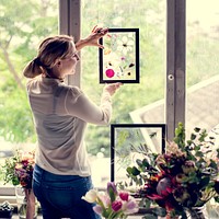Florist woman holding frame of pressed flower