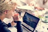Woman Sipping Coffee while Working on Laptop