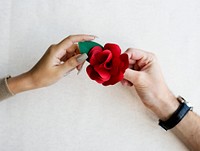 Hands holding a paper crafted red rose