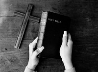 Female hands holding a bible and a wooden cross