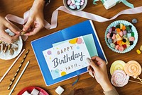 Hand Holding Birthday Wish Card on Wooden Table Background with Sweet Snacks