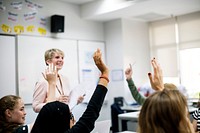 Students with their hands up responding to their teacher