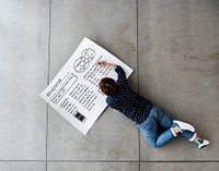 Female laying on the floor writing on a poster.