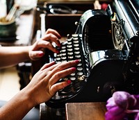 Woman typing vintage typewriter on wooden table