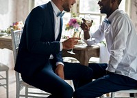 Gay couple having champagne at wedding reception