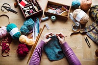 Aerial view of hands knitting on wooden table