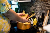 Hands cooking pasta in a pot