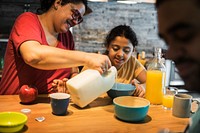 Mom pouring milk in daughter's cereal