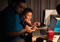 Dad with little girl working on laptop in a home office