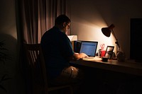 Man working in a dark home office with a laptop