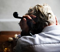 Rear view of caucasian man sitting down with a pipe 