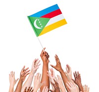 Group Of Multi-Ethnic People Reaching For And Holding The Flag Of Comoros.
