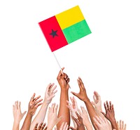 Group of multi-ethnic people reaching for and holding the flag of Guinea Bissau.