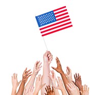Group of multi-ethnic people reaching for and holding the flag of the United States of America.