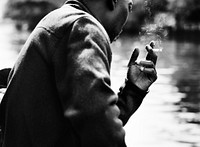 Guy smoking and sitting by the water