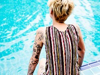 Rear view of caucasian tattooed woman sitting by the pool