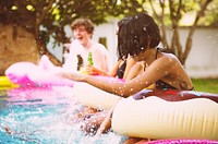 Group of diverse friends enjoying the pool with inflatable tubes