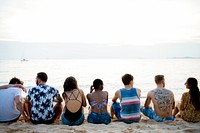 Rear view of diverse friends sitting at the beach together