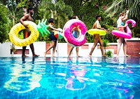 Group of diverse friends enjoying summer time by the pool with inflatable tubes