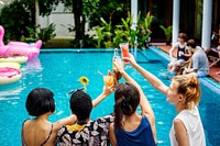 Group of friends cheers drinks at the pool