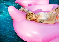 Caucasian tattooed woman floating in the swimming pool by inflatable