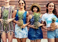 Group of diverse women standing holding pineapple together