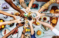 Aerial view of diverse hands clinking beverage together