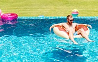 A Caucasian tattooed man on an inflatable float in the swimming pool