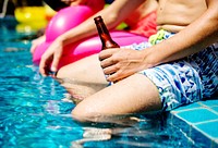 Closeup of man hand holding beer bottle by the poolside