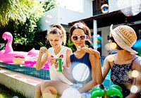 A diverse group of female friends enjoying summer time by the pool and playing with a soap bubbler