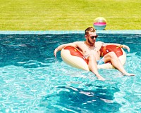 Caucasian tattooed man floating in the swimming pool by inflatable