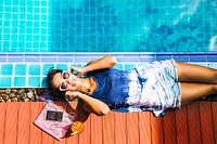 Asian woman sunbath and listening music at the pool