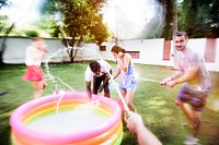 Diverse young adult splashing water in backyard