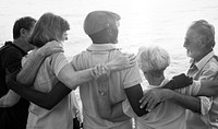 Group of senior friends arm around on the beach