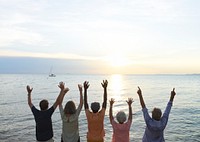 Senior group firnds arm raised on the sunset beach