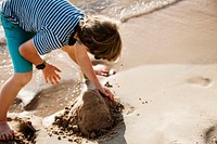 Closeup of caucasian boy playing with the sand at the beach