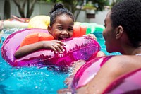 Closeup of black mother and daughter enjoying the pool with inflatable tubes