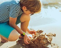 Little boy playing sand by the seashore