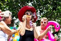 Group of diverse senior adults sitting at poolside blowing soap bubbles