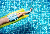 Young caucasian boy enjoying floating in the pool on pool inflatable bed