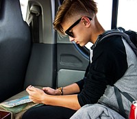 Young caucasian traveler boy sitting in a van using mobile phone
