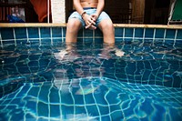 Teenage boy sitting near swimming pool